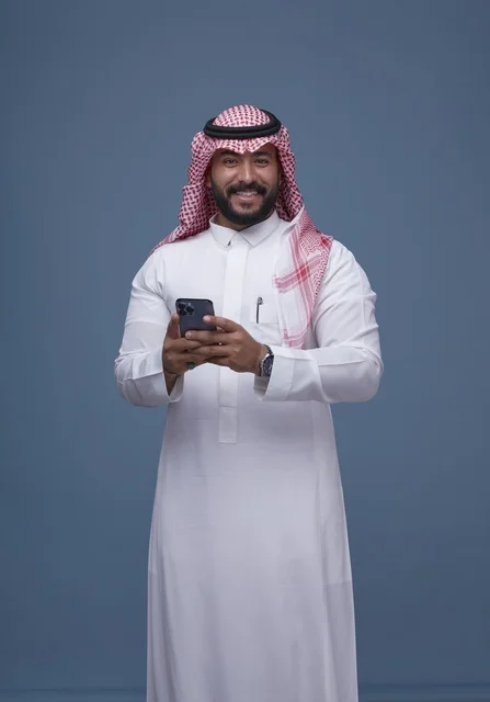 Smiling Saudi Man in Traditional Dress Using Smartphone