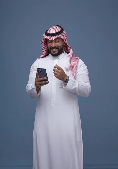 رجل سعودي بالزي التقليدي يستخدم الهاتف الذكي في الاستوديو