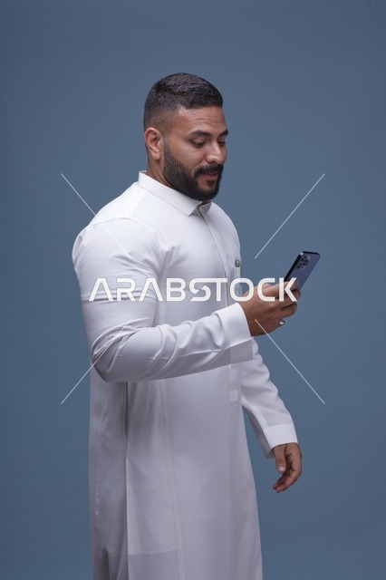 رجل سعودي بالثوب الأبيض يستخدم الهاتف الذكي
