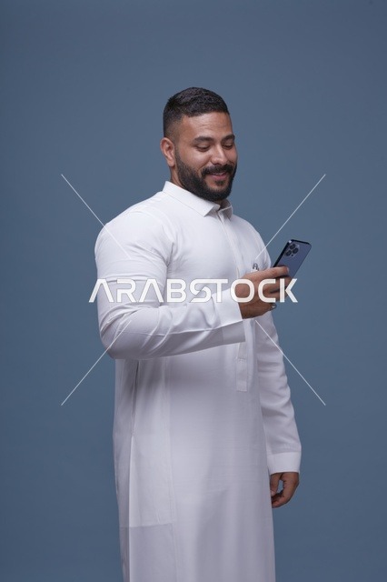 رجل سعودي يستخدم الهاتف الذكي مرتدياً ثوباً أبيض