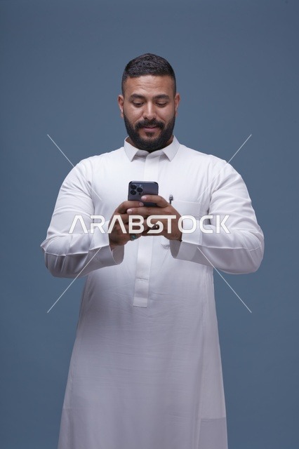 رجل سعودي يستخدم الهاتف الذكي مرتدياً ثوباً أبيض