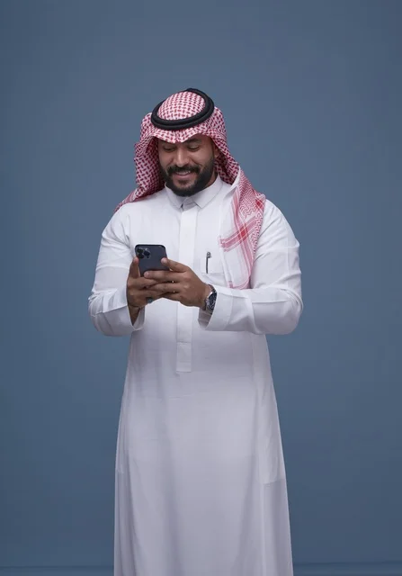 Smiling Saudi Man with Smartphone in Traditional Dress