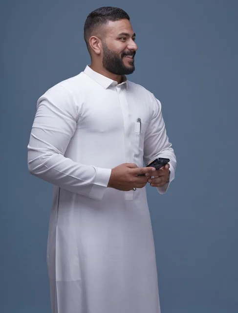 رجل سعودي بالثوب الأبيض يستخدم الهاتف الذكي خلفية زرقاء