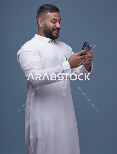 رجل سعودي بالثوب الأبيض يستخدم الهاتف الذكي