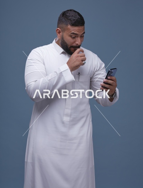 رجل سعودي بالثوب الأبيض يستخدم الهاتف الذكي