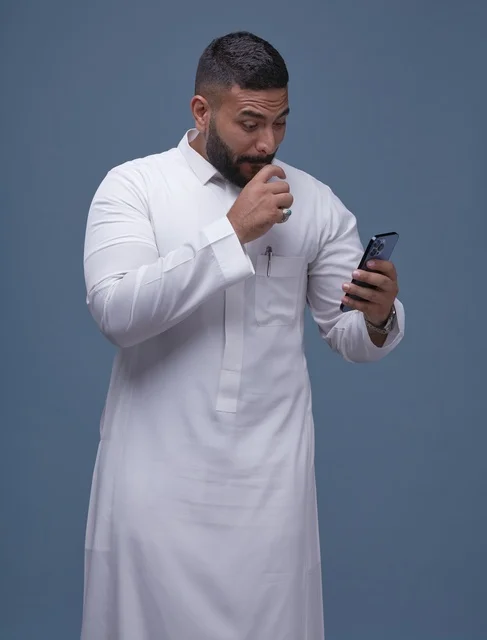Saudi Man in White Thobe using Smartphone