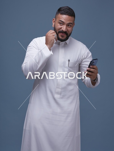 رجل سعودي بالثوب الأبيض يستخدم الهاتف الذكي