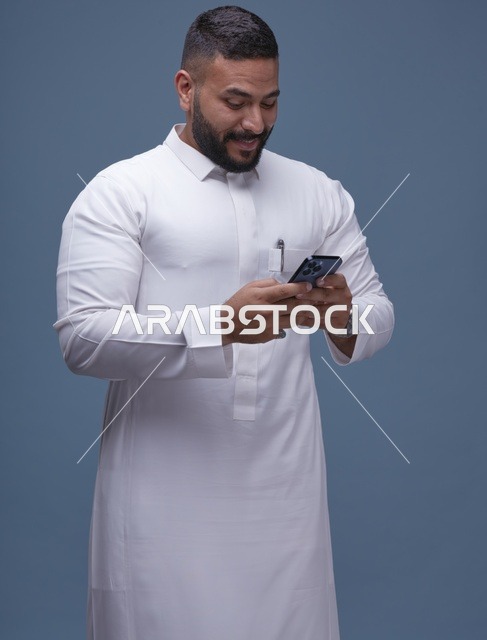 رجل سعودي بالثوب الأبيض يستخدم الهاتف الذكي