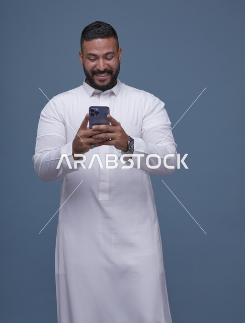 رجل سعودي بالثوب الأبيض يستخدم الهاتف الذكي