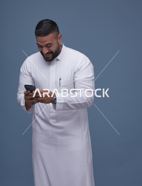 رجل سعودي يرتدي الثوب الأبيض يستخدم الهاتف الذكي