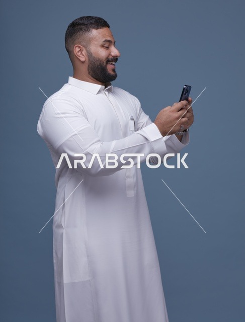 رجل سعودي بالثوب الأبيض يستخدم الهاتف الذكي