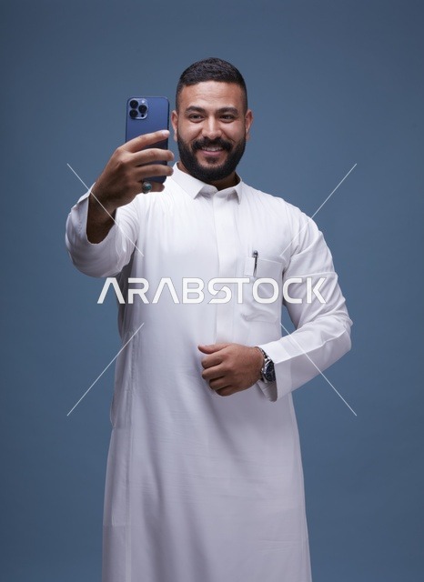 Saudi Man in White Thobe Taking Selfie with Smartphone