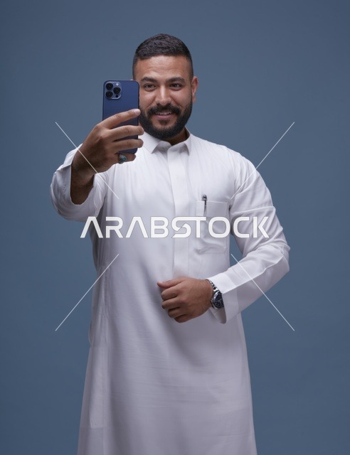 رجل سعودي بالثوب الأبيض يلتقط سيلفي بالجوال
