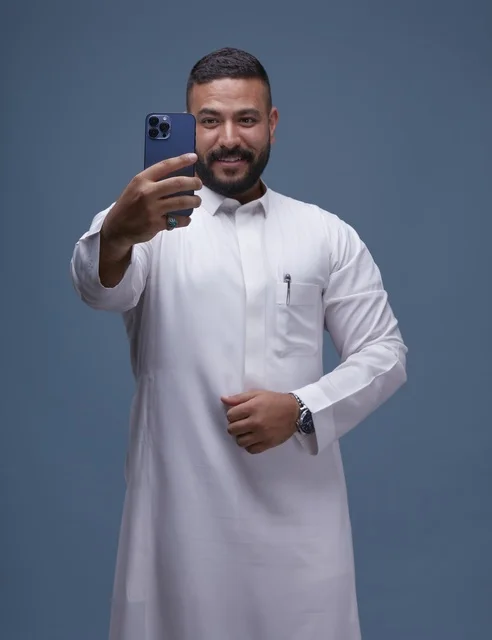 رجل سعودي بالثوب الأبيض يلتقط سيلفي بالجوال
