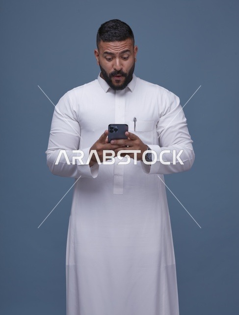 رجل سعودي بالثوب الأبيض متفاجئ من الهاتف الذكي