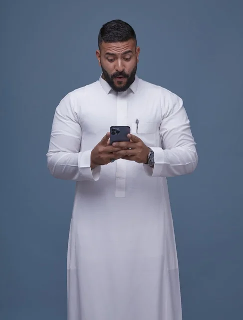 رجل سعودي بالثوب الأبيض متفاجئ من الهاتف الذكي