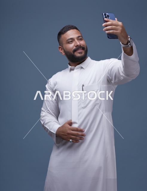 رجل سعودي بالثوب الأبيض يلتقط سيلفي بالهاتف
