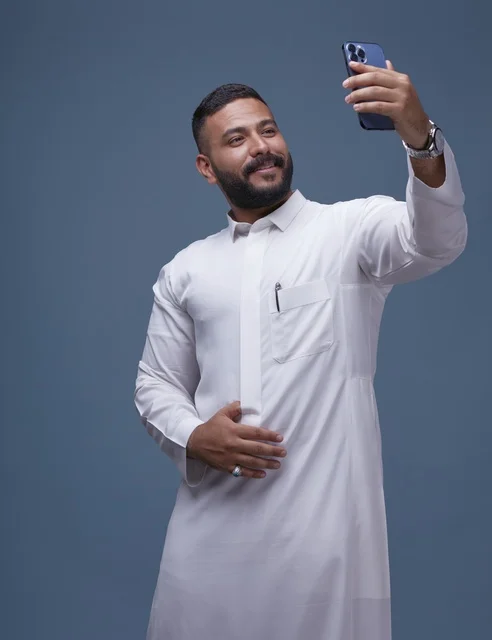 Saudi Man in White Thobe Taking Selfie on Smartphone