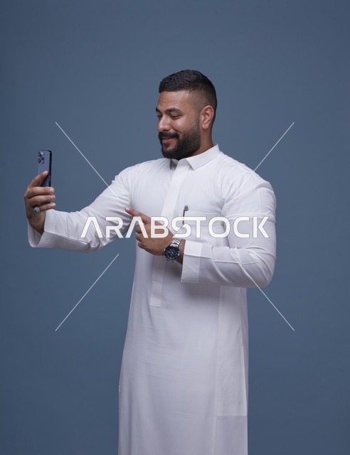 رجل سعودي بالثوب الأبيض يلتقط سيلفي بالجوال