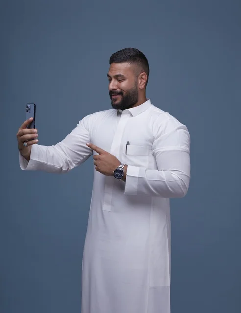 Saudi Man in White Thobe Taking Selfie on Smartphone