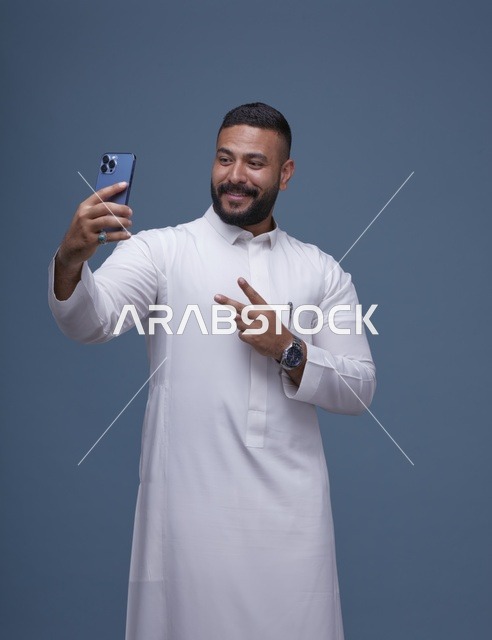 رجل سعودي بالثوب الأبيض يلتقط سيلفي في استوديو