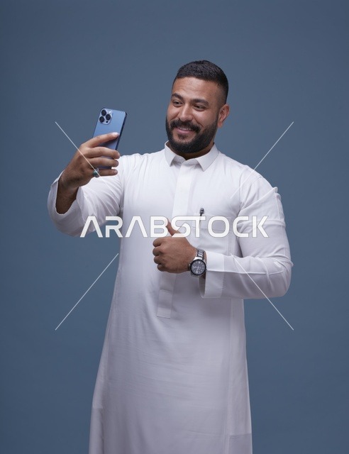 رجل سعودي بالثوب الأبيض يلتقط سيلفي مع إيماءة الإعجاب