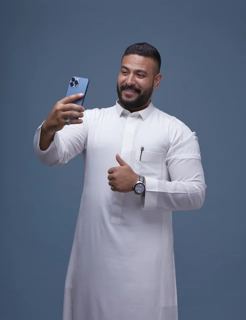 رجل سعودي بالثوب الأبيض يلتقط سيلفي مع إيماءة الإعجاب