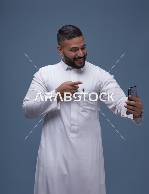 Smiling Saudi Man in Thobe Taking Selfie on Smartphone