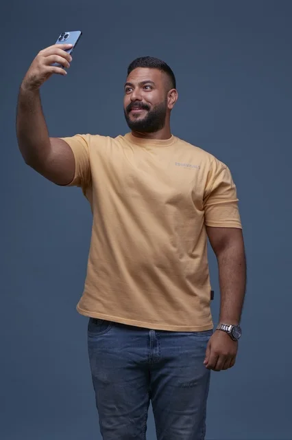 Saudi Man Taking Selfie in Yellow Shirt Blue Background