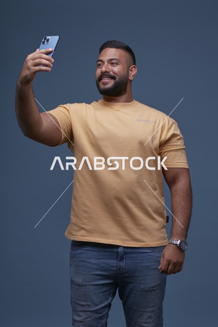 رجل سعودي يلتقط سيلفي بهاتف ذكي في الاستوديو