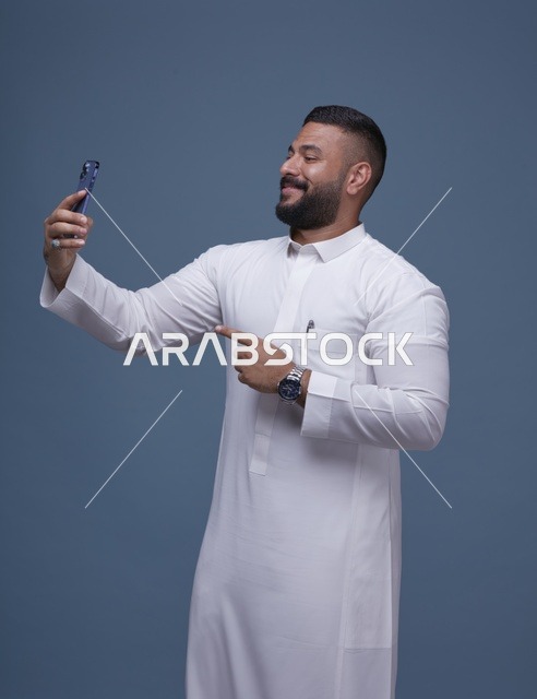 رجل سعودي يلتقط سيلفي بالثوب الأبيض في استوديو