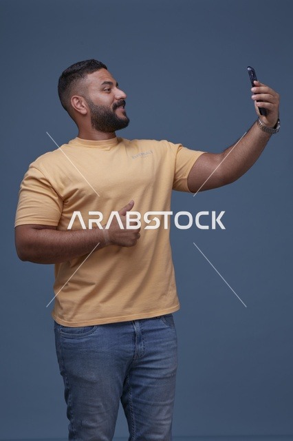 رجل سعودي يلتقط سيلفي مع إشارة الإعجاب في استوديو