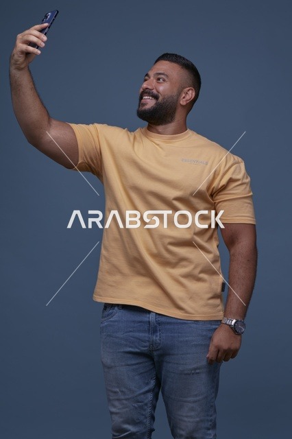رجل سعودي يلتقط سيلفي بالهاتف بملابس كاجوال
