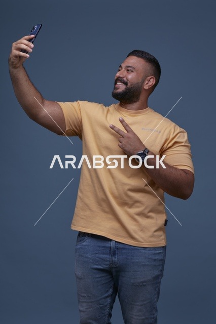 رجل سعودي يلتقط سيلفي بإشارة النصر بملابس كاجوال