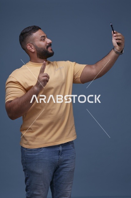 رجل سعودي يلتقط صورة سيلفي بالهاتف الذكي في الاستوديو