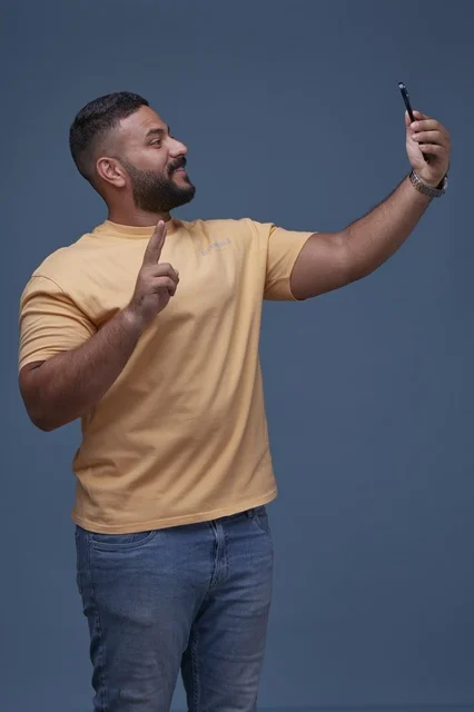 رجل سعودي يلتقط صورة سيلفي بالهاتف الذكي في الاستوديو