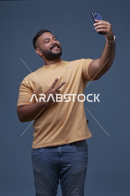 رجل سعودي يلتقط سيلفي بإشارة النصر على خلفية زرقاء
