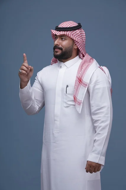 رجل سعودي بالزي التقليدي يشير للأعلى في الاستوديو