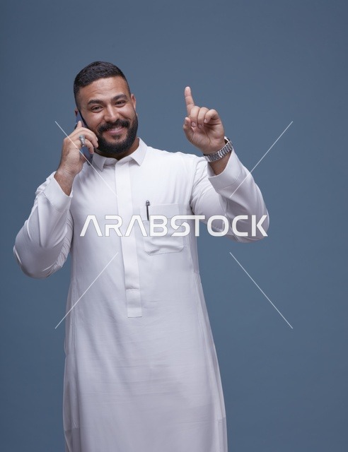 رجل سعودي بالثوب الأبيض يتحدث بالهاتف الذكي