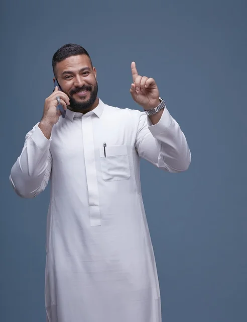 رجل سعودي بالثوب الأبيض يتحدث بالهاتف الذكي