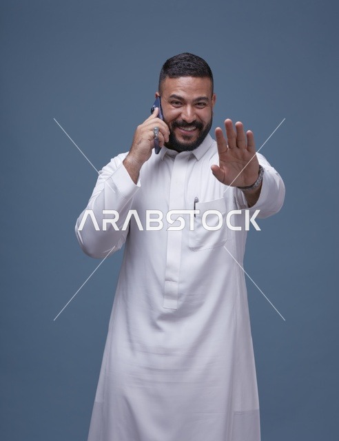 رجل سعودي بالثوب الأبيض يتحدث بالهاتف الذكي