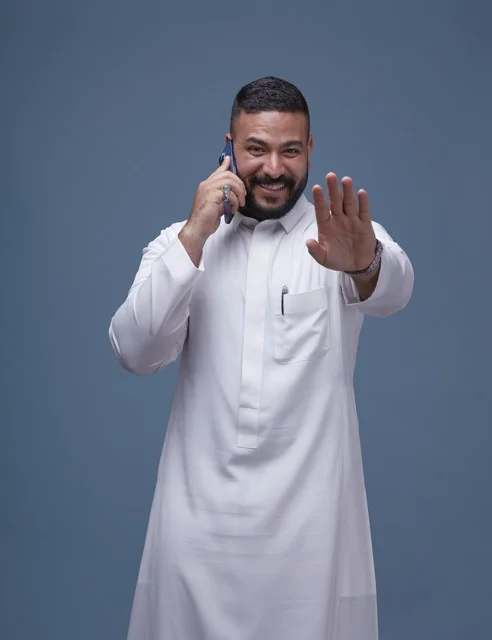 رجل سعودي بالثوب الأبيض يتحدث بالهاتف الذكي