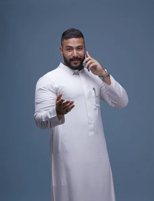 Saudi Man in Traditional White Thobe Talking on Smartphone