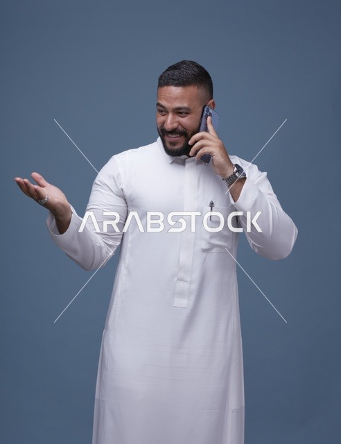 رجل سعودي بالثوب الأبيض يتحدث بالهاتف الذكي