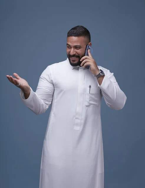 Saudi Man in White Thobe Talking on Smartphone