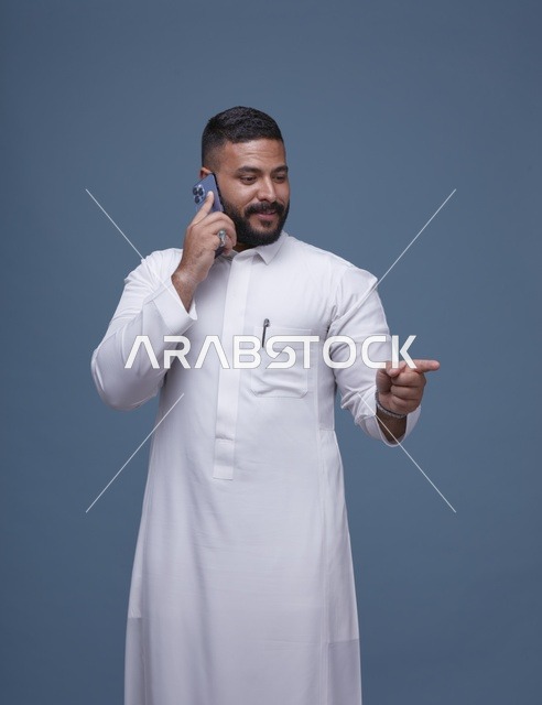 رجل سعودي بالثوب الأبيض يتحدث بالهاتف الذكي استوديو
