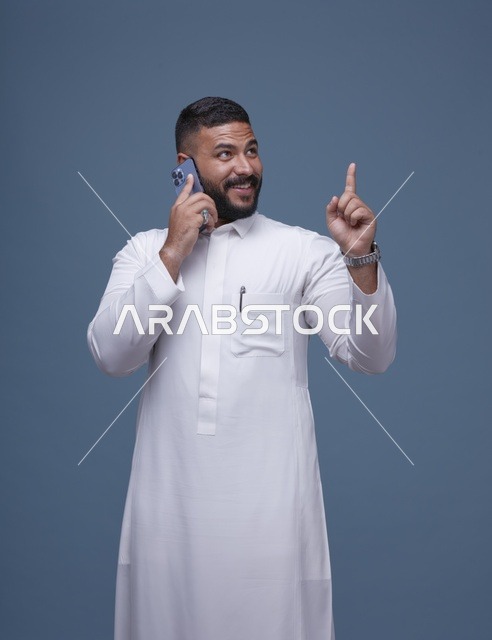 رجل سعودي بالثوب الأبيض يتحدث بالهاتف ويشير للأعلى