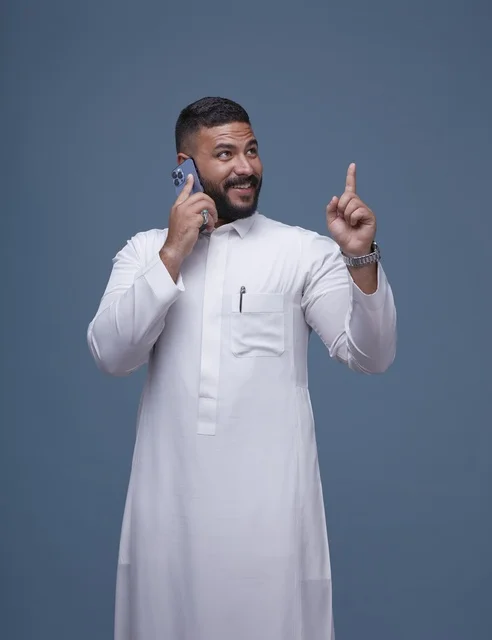 رجل سعودي بالثوب الأبيض يتحدث بالهاتف ويشير للأعلى