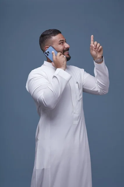 Saudi Man in White Thobe Using Smartphone