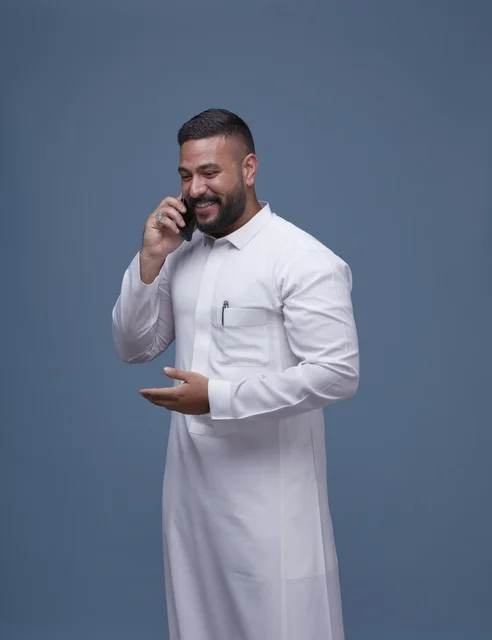 رجل سعودي بالثوب الأبيض يتحدث عبر الهاتف الذكي